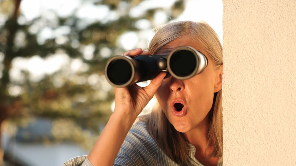 old woman spying on the neighbors with binoculars