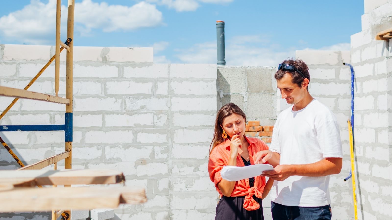 Man Oversees Construction of Dream Home, but Constant Input From His Wife Starts Causing Friction couple looking at blueprints in house that's under construction