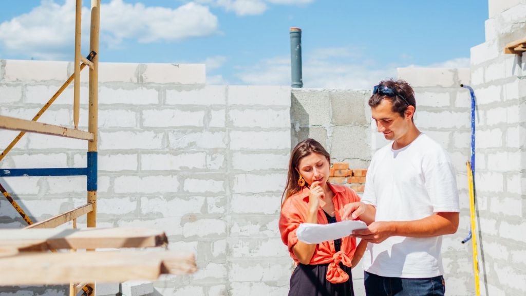 couple looking at blueprints in house that's under construction