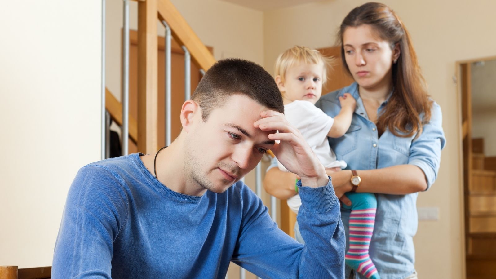 Man Considers Working Overtime to Pay for Trip After Wife Criticizes the Cost of Visiting a Friend man looking upset while his wife holds a toddler