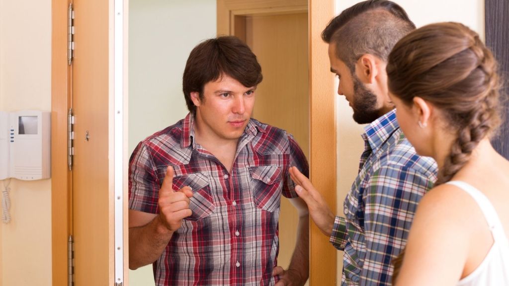 man arguing with couple in doorway