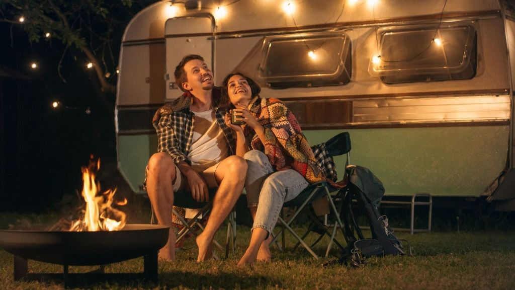 couple sitting outside a camper at night