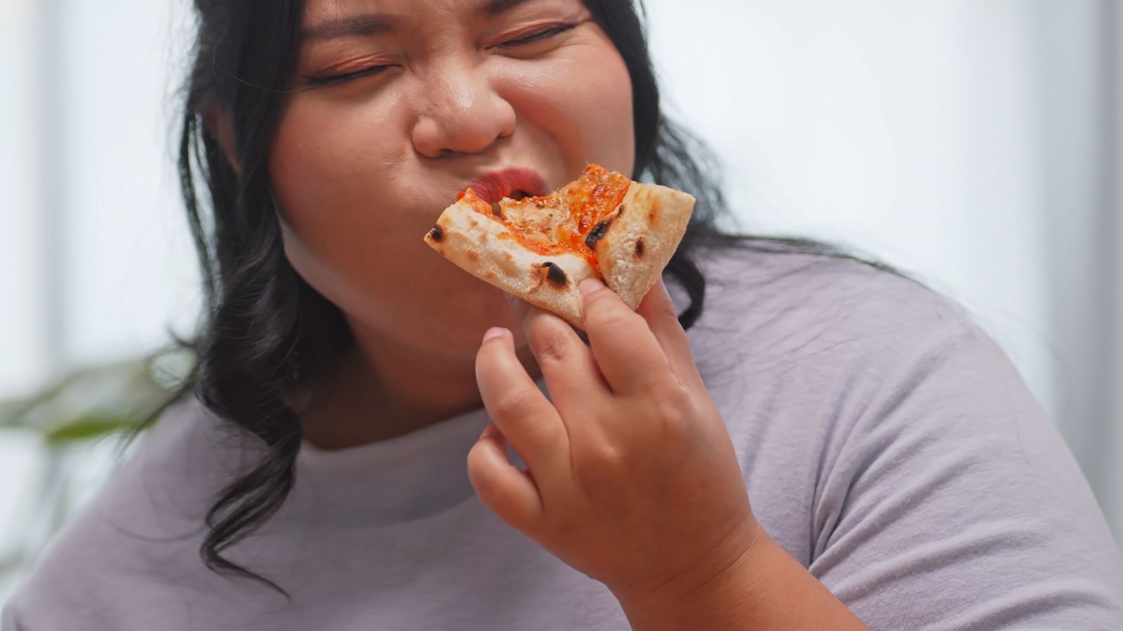 The Accidental Confession: Shoplifting Suspect Blunders Her Way Into Handcuffs After Blabbing to Police closeup of overweight woman eating pizza