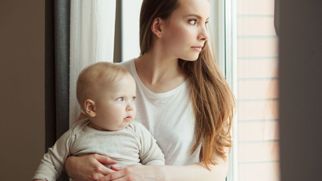 woman holding baby and looking out the window