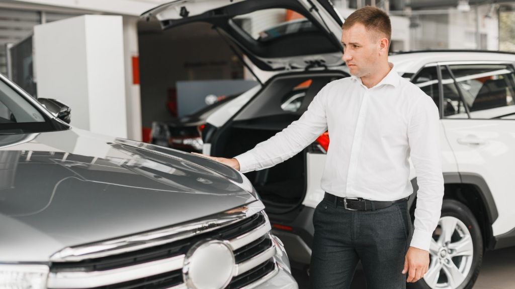 man looking at a car at a car dealership