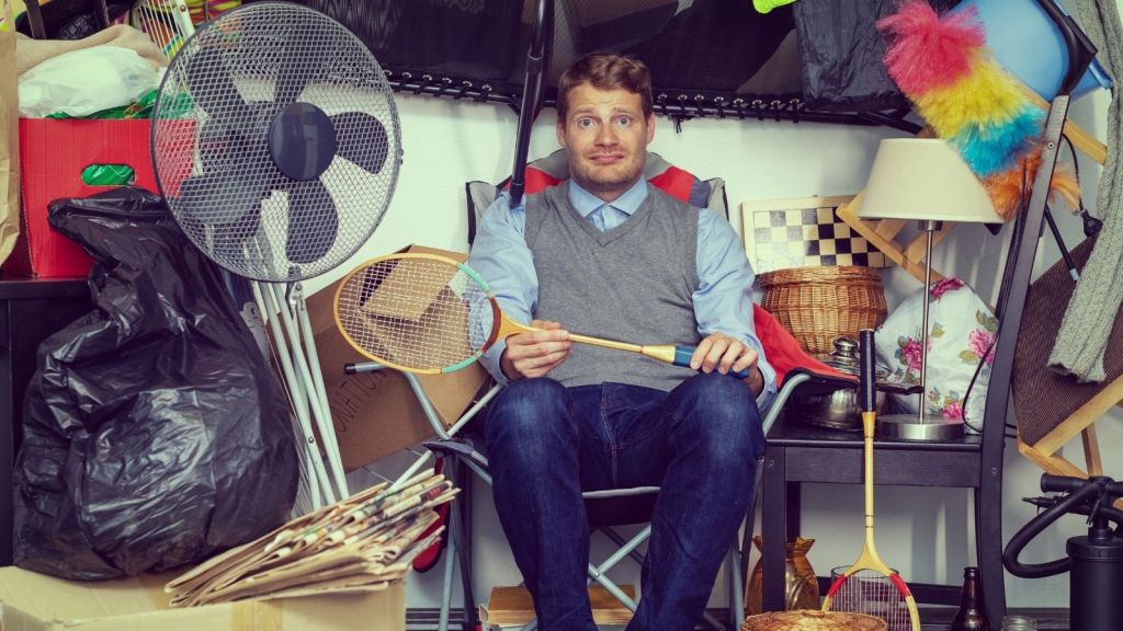 man surrounded by random junk