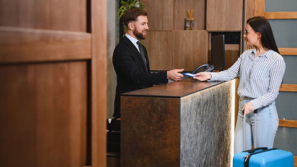 man working at a hotel front desk checking in a guest