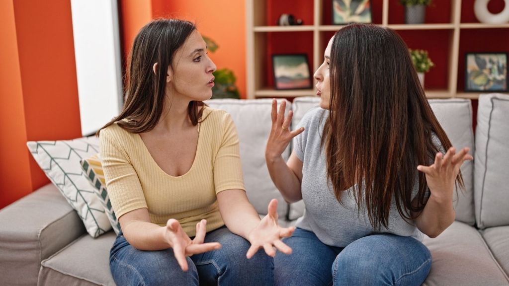 two women sitting on a couch arguing