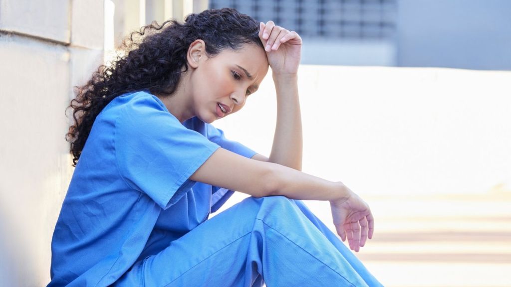 stressed out nurse sitting on the ground outside