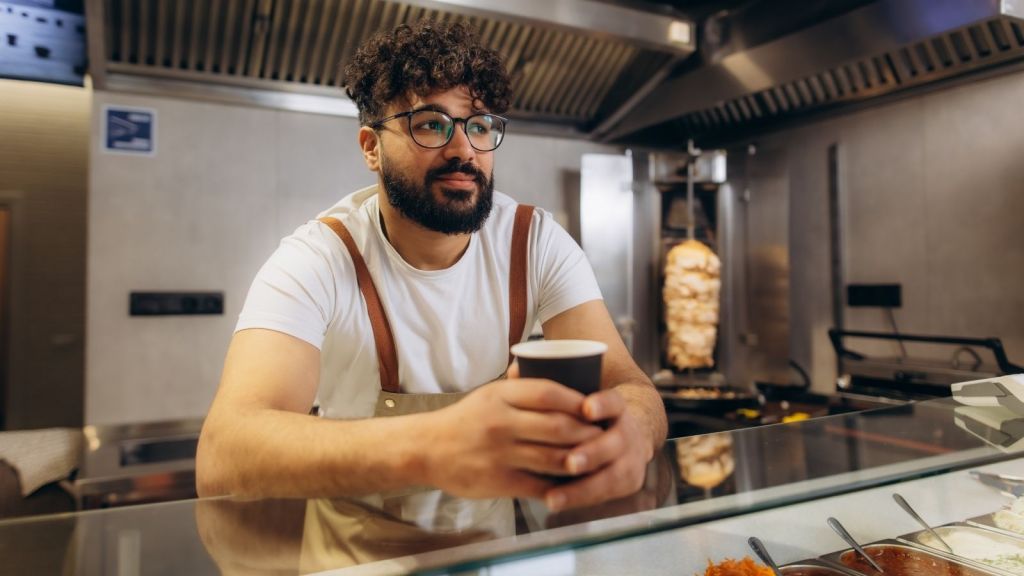 man holding coffee cup in restaurant kitchen