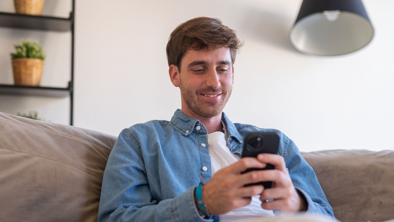 man sitting on couch looking at his phone