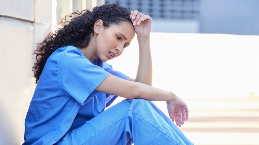 tired nurse sitting on the ground outside