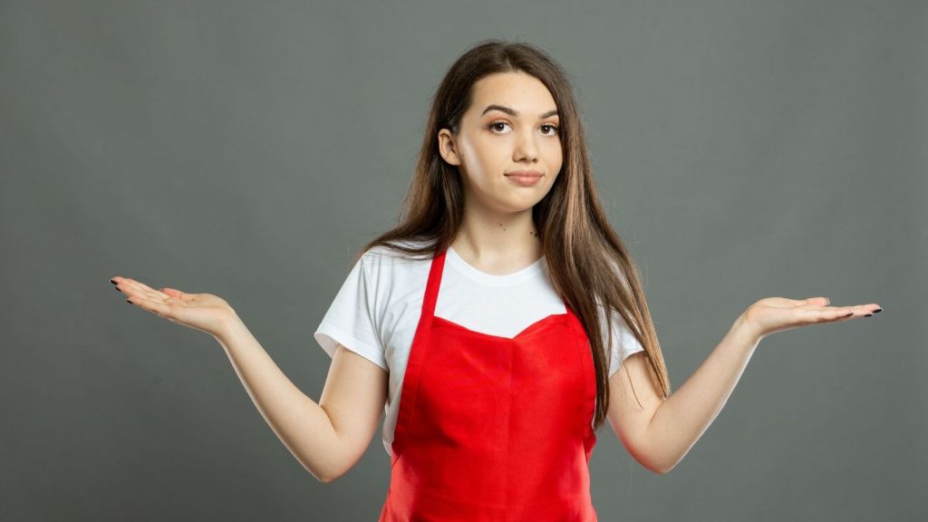 young woman in a red apron shrugging