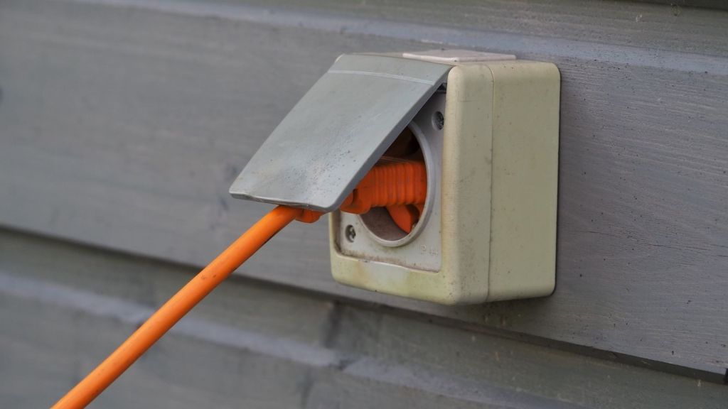 orange extension cord plugged into outdoor electrical outlet