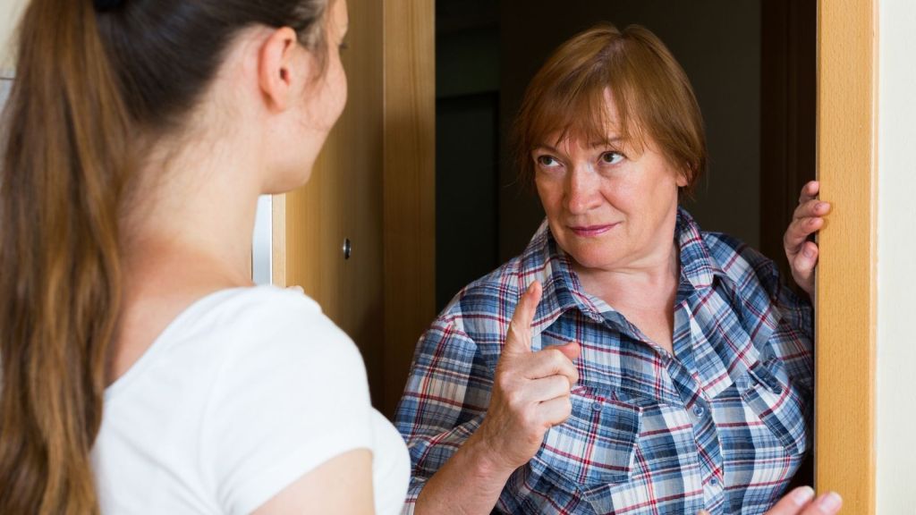 angry older woman pointing at younger woman in doorway