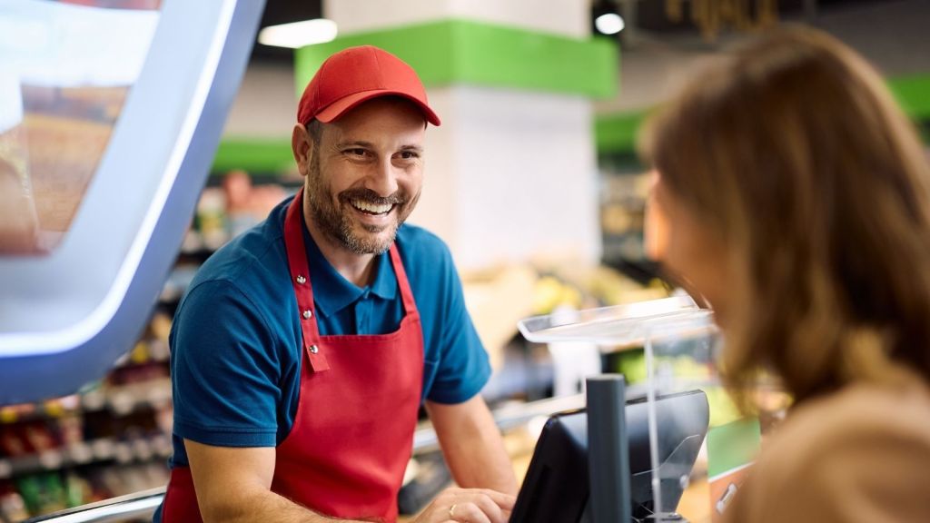 smiling man working as a cashier at a grocery store