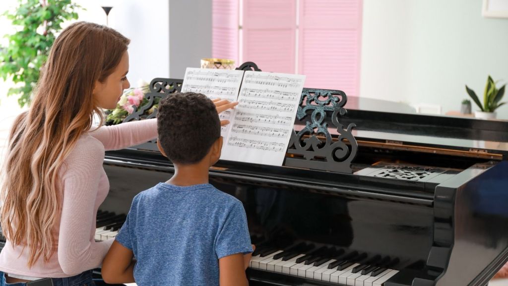 woman giving little boy piano lesson