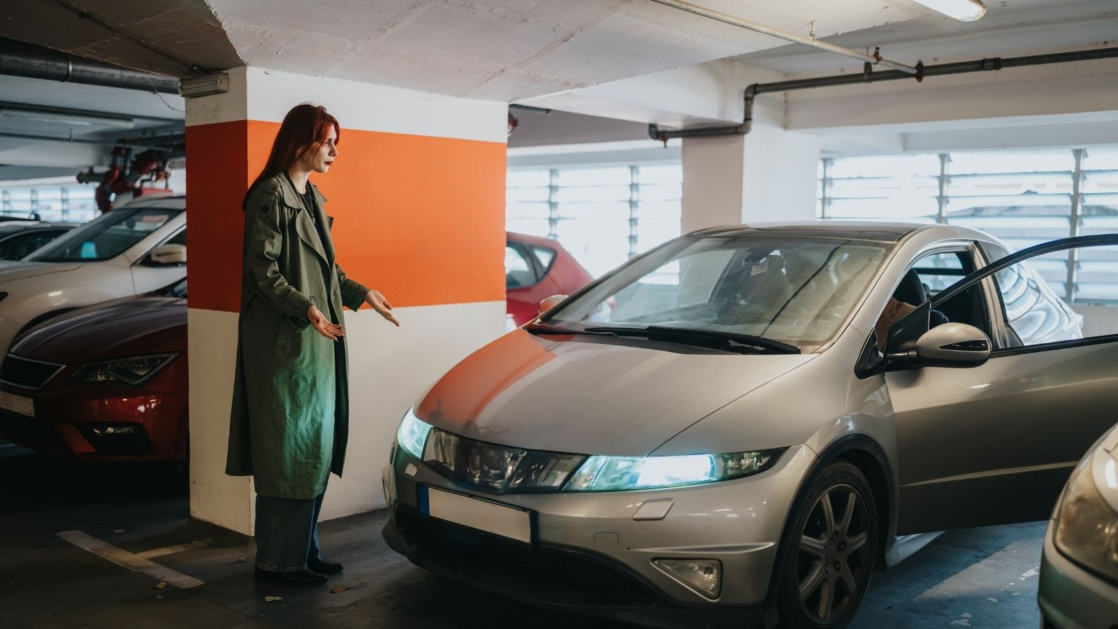 woman stands beside car in parking garage