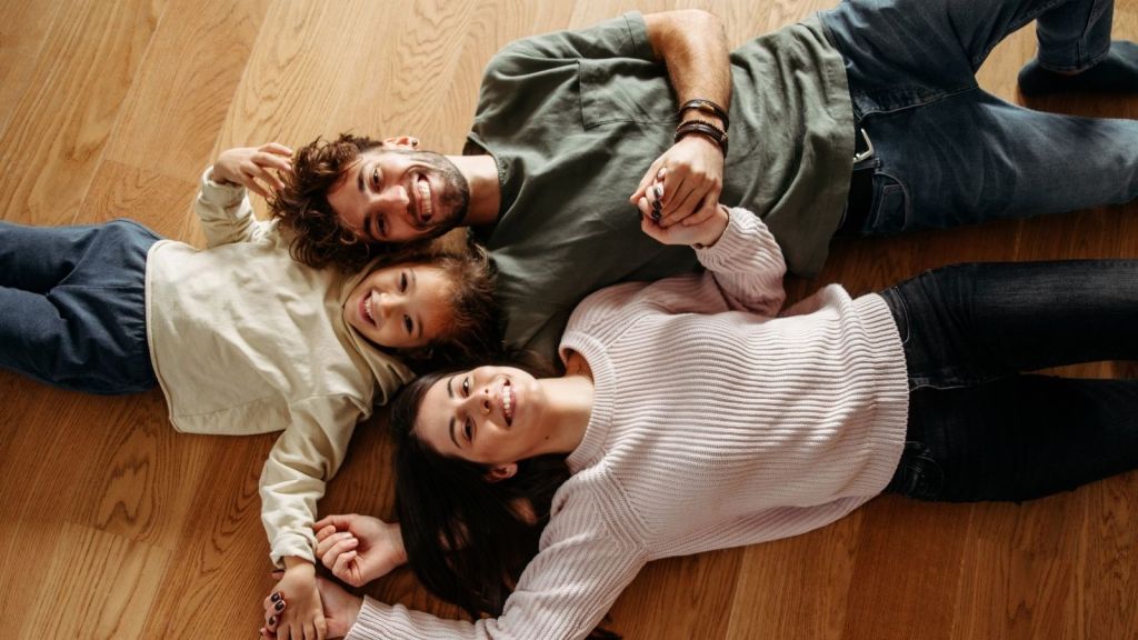 mom, dad and little girl lying on hardwood floors