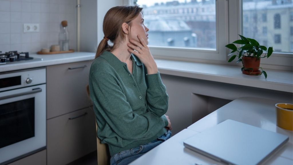 woman looking out the window while working from home
