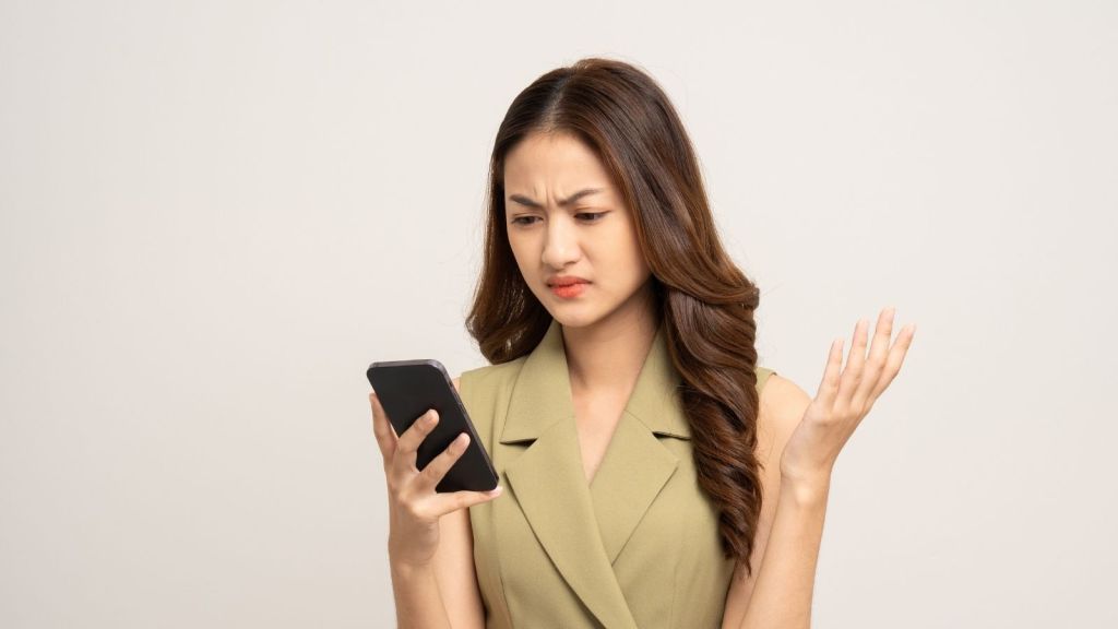 stressed out young woman looking at her phone