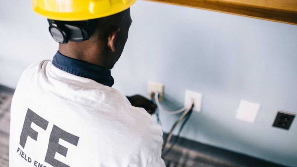 A field engineer in a hard hat working on electrical installation indoors