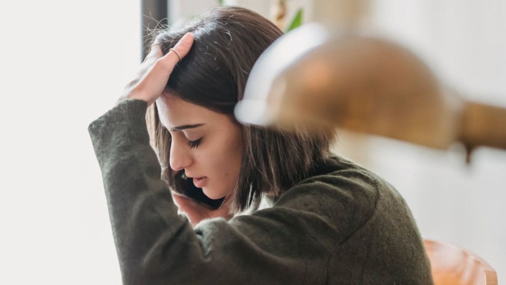 Woman feeling sad while talking to someone on the phone