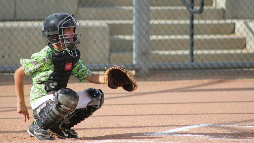 Young boy playing as a baseball catcher, crouched and ready during a daytime game