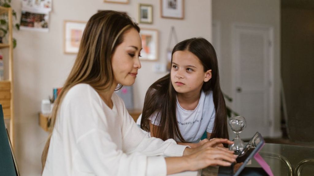 Young girl talking to her mother who is working
