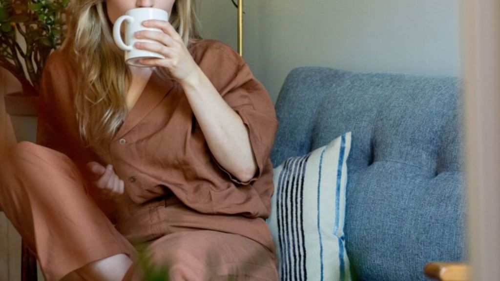 Woman drinking from a mug while sitting on her couch