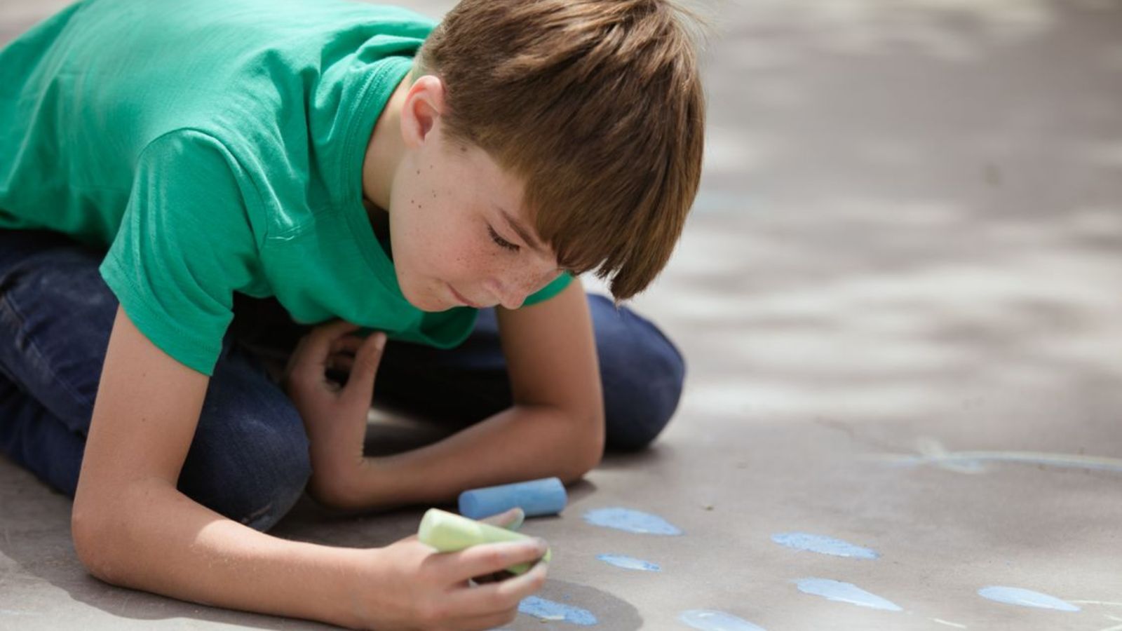 Woman Discovers Neighbor Kids Are Crossing Boundaries Around Her Porch and Packages Boy wearing green shirt drawing on the pavement with chalk