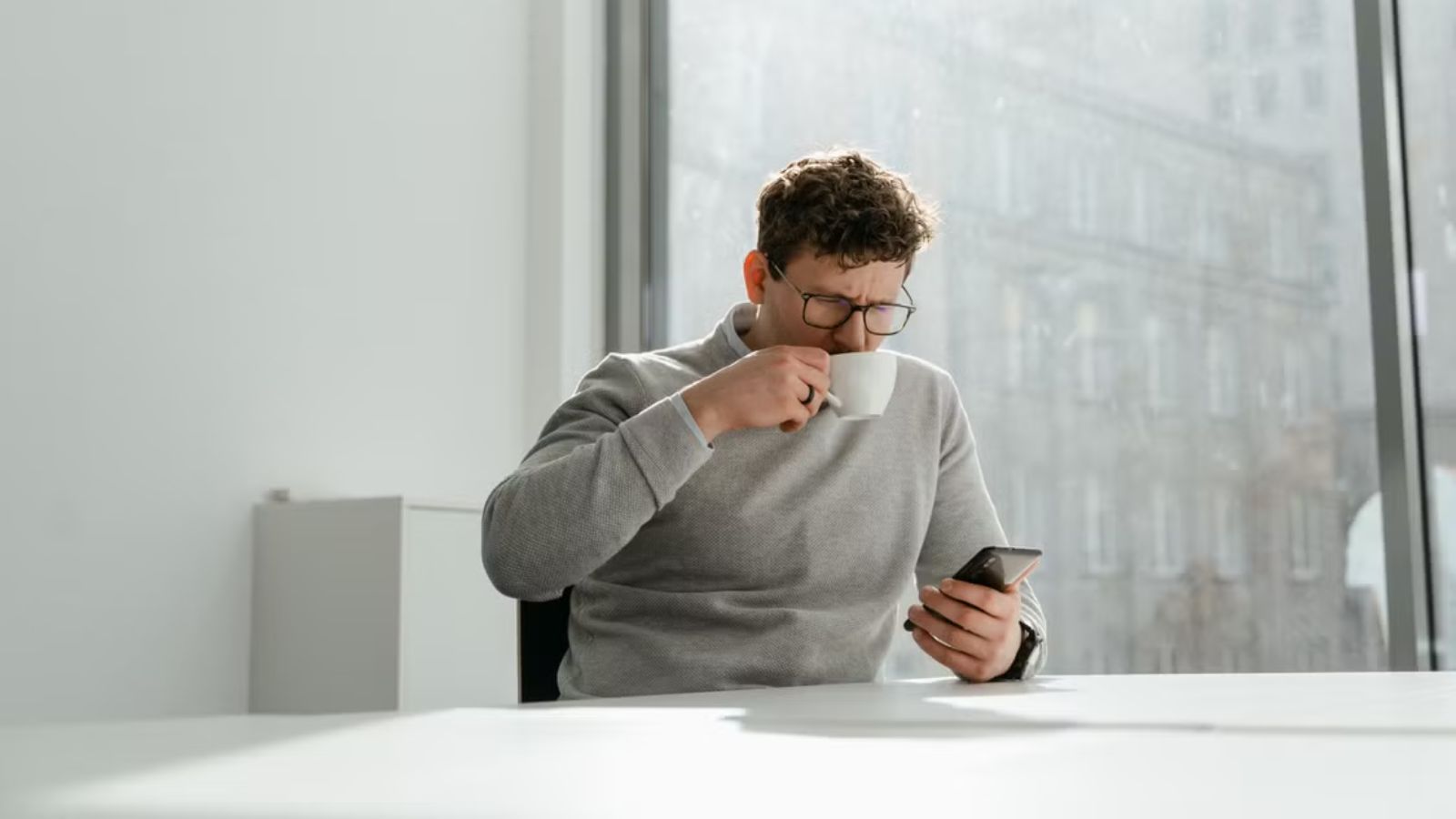 From Star Employee to Quiet Quitter: How One Worker Mastered the Art of the Bare Minimum Man having coffee while using his mobile phone in the office