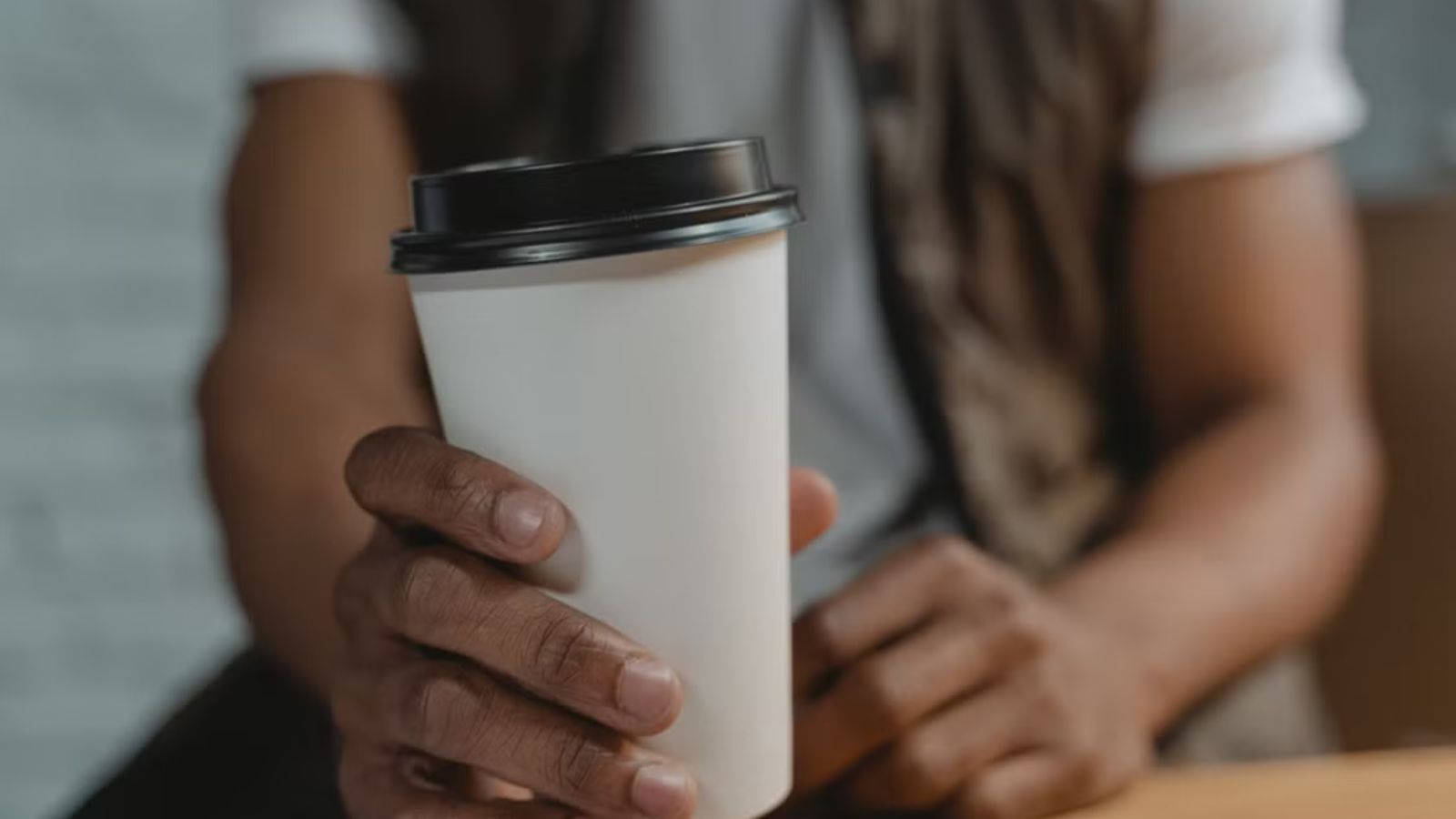 Man Pushes Back After Manager’s Strict Coffee Cup Rule Leads to a Clever Workaround Man holding a to-go coffee cup