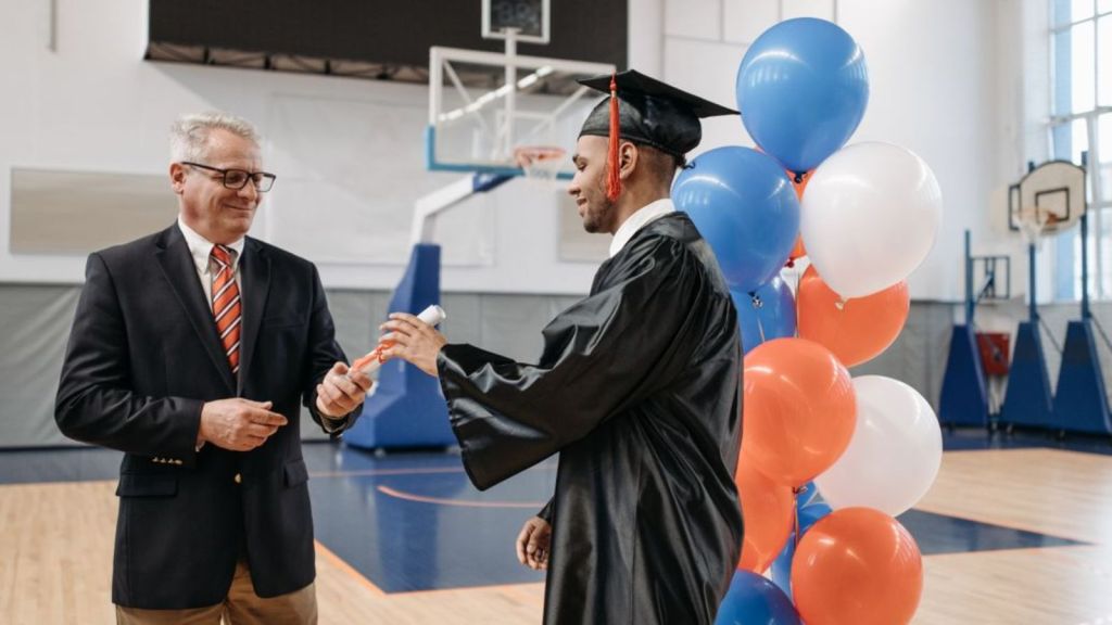 Teenager graduating from high school and receiving his diploma from a school authority