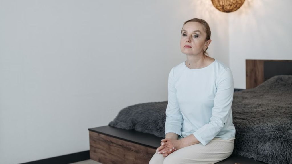 A sad woman sitting on the edge of the bed