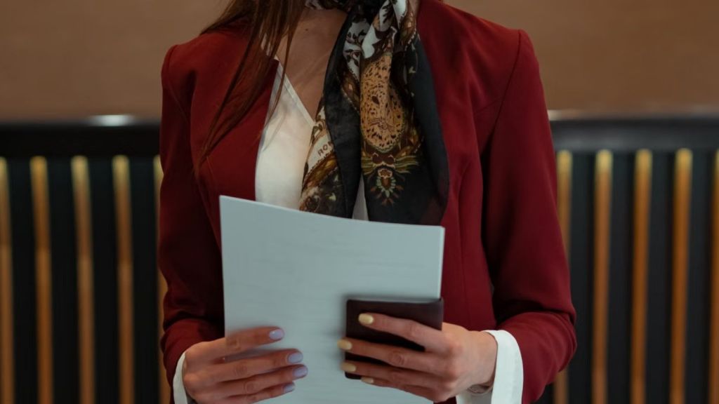 Hotel receptionist holding documents and wallet in formal attire