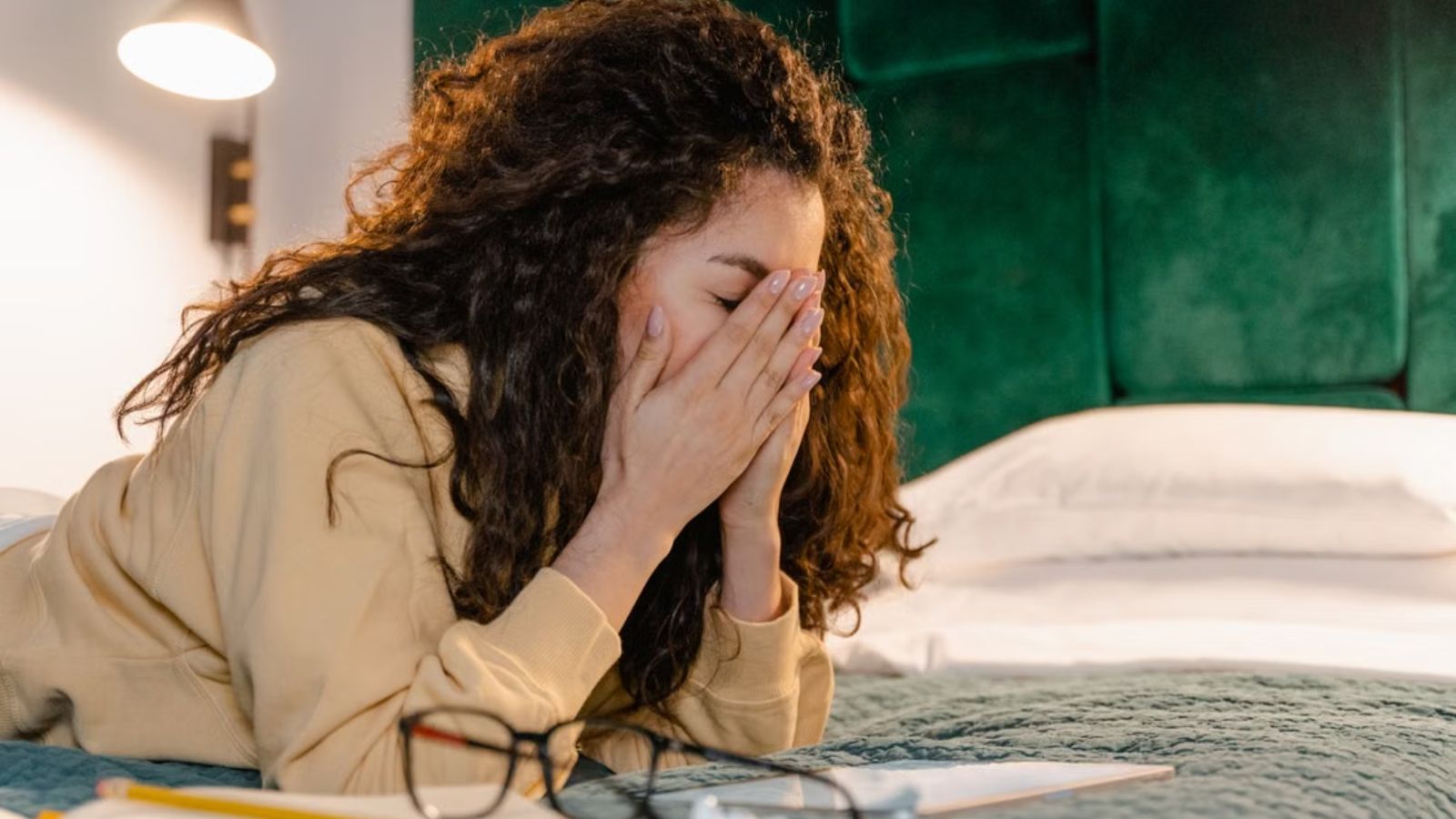 Woman covering her face and feeling stressed while on the bed