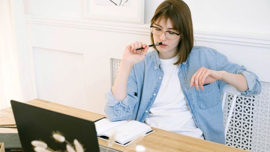 Woman thinking about what to write in front of her laptop