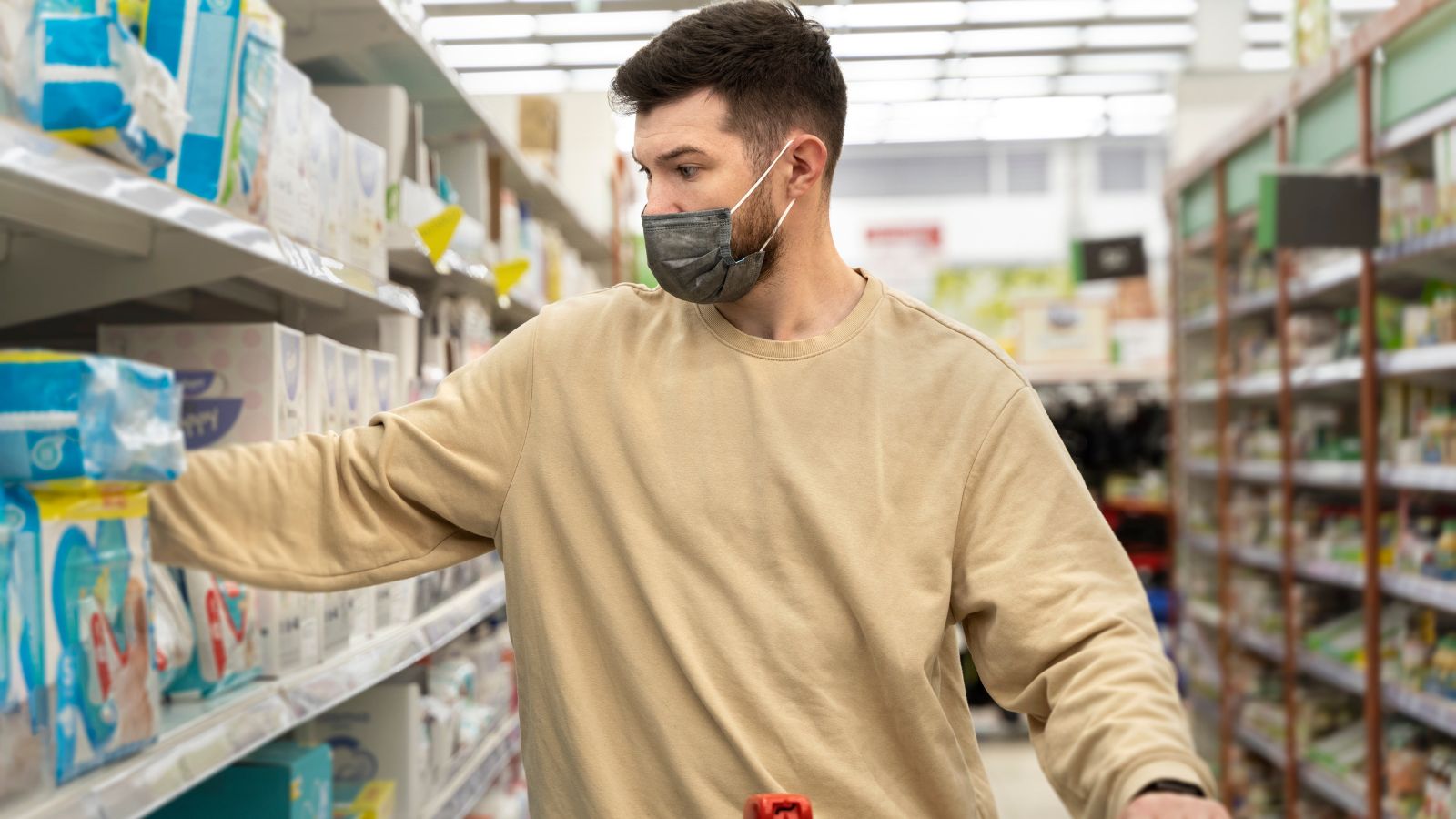 Man wearing face mask and long sleeve shirt doing some grocery shopping