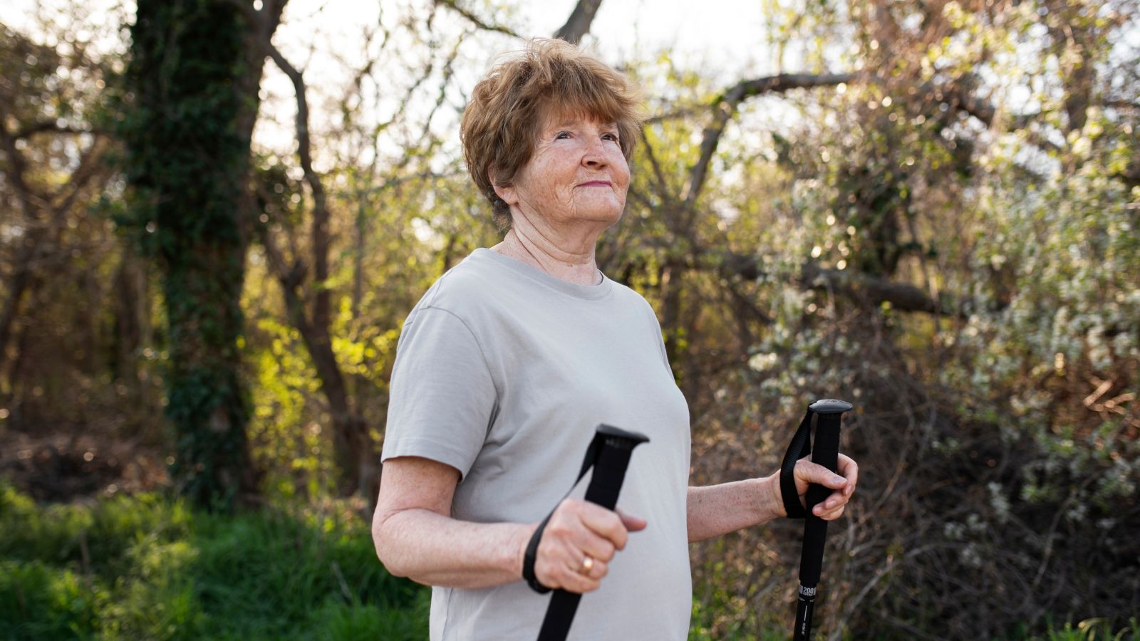 Elderly woman wlaking outdoors with walking sticks