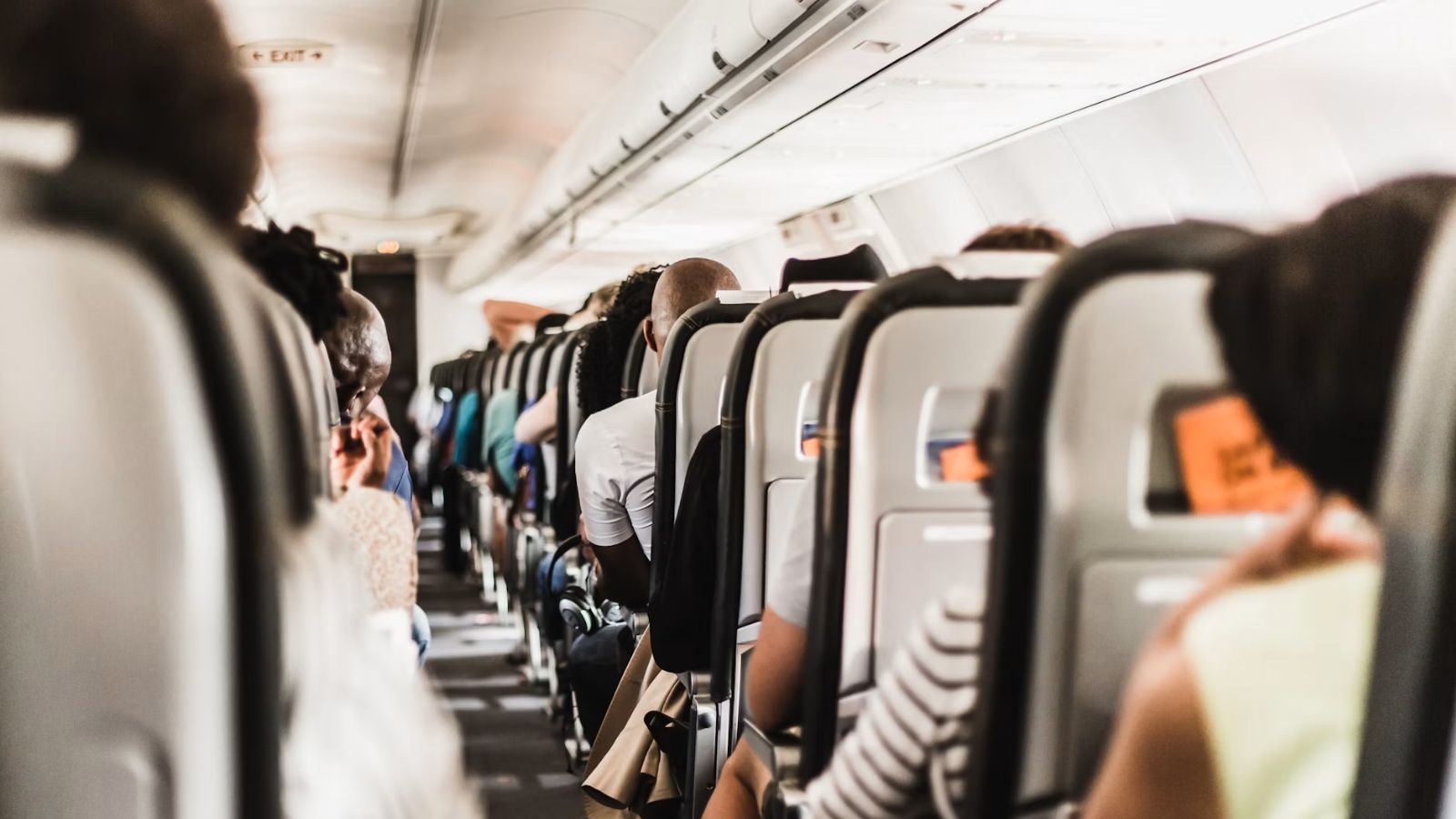The aisle of an airplane with passengers sitting on economy seats