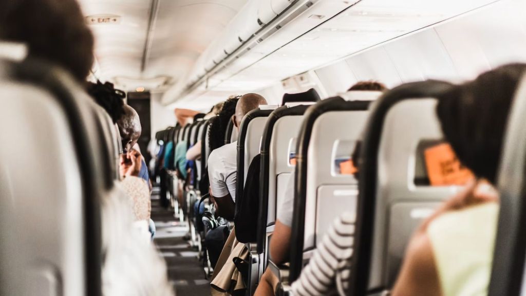 The aisle of an airplane with passengers sitting on economy seats