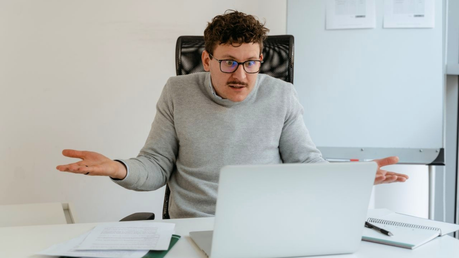 Upset man gesturing at his laptop
