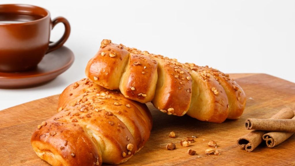 Two loaves of cinnamon bread topped with nuts and a cup of coffee on the side