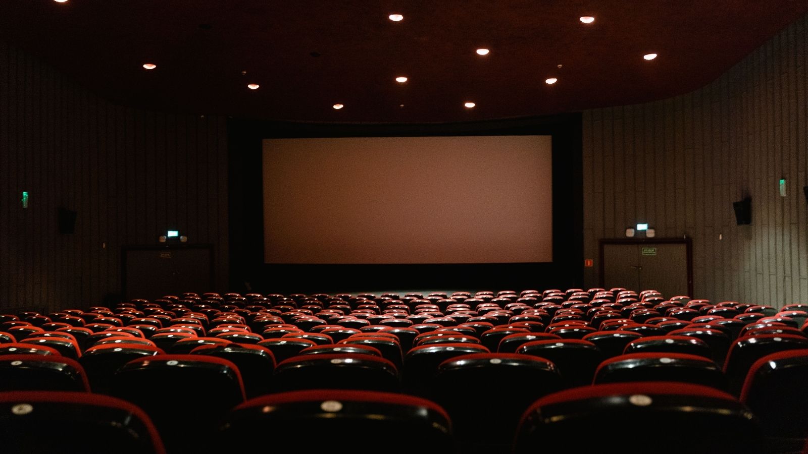 Empty movie theater seats facing a big screen