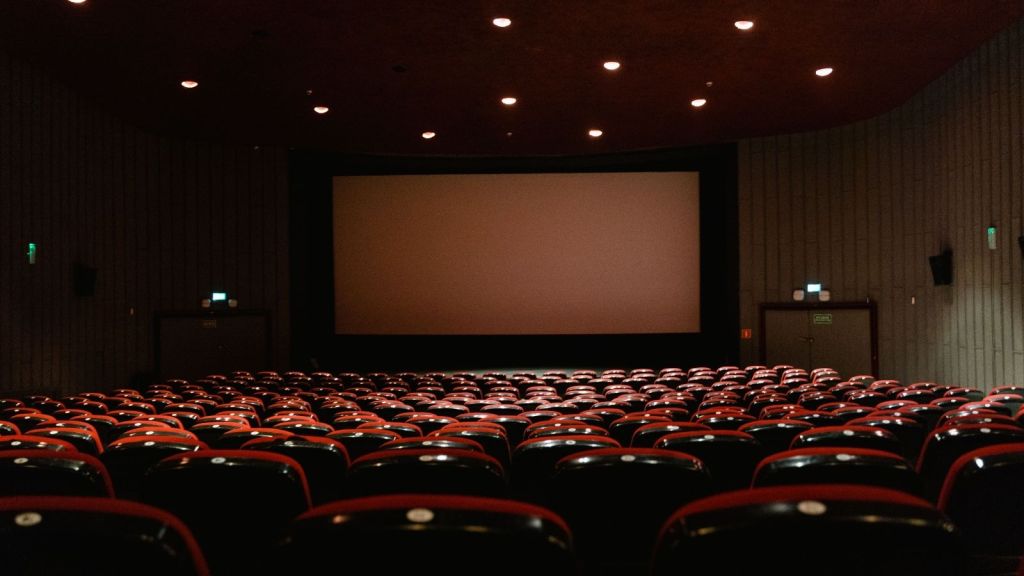 Empty movie theater seats facing a big screen