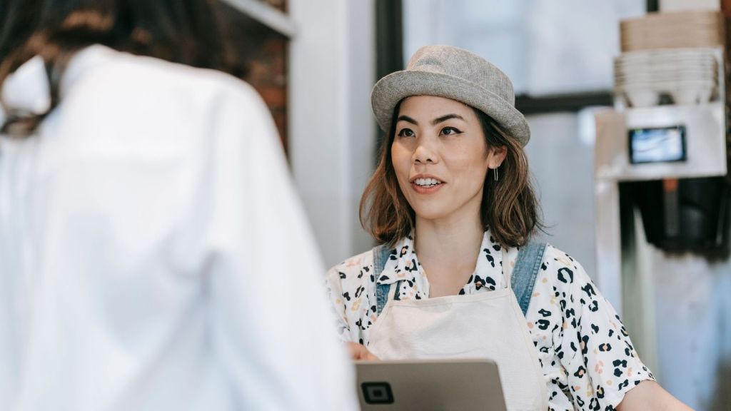Woman at cashier listening to person opposite her