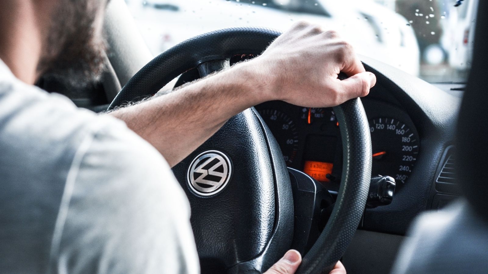 Furious Parking Lot Clash Explodes After Driver Refuses to Help a Terrified Woman Who Dropped Her Groceries Over His Car Alarm Man turning steering wheel in his car