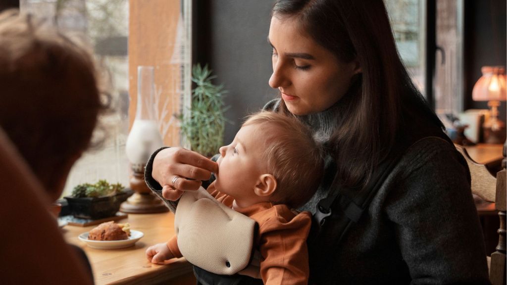 Woman carrying a baby and feeding her in a restaurant
