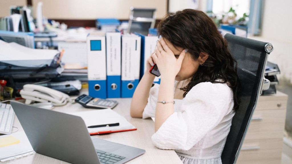 Woman talking on the phone and covering her face while in the office